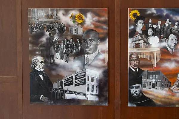 The first panel of the mural featuring dark historical photos.