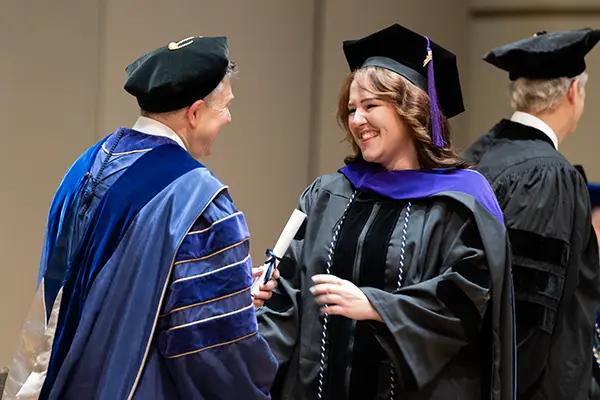 A student accepts an award on stage during the Washburn Law commencement ceremony.