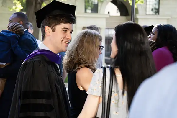 A graduate smiles while talking to friends after the ceremony.