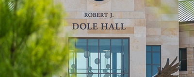 Dole Hall sign above north entrance of building with green tree unfocused in foreground