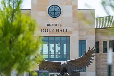 Dole Hall north entrance with eagle sculpture and green tree unfocused in foreground