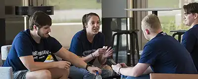 4 students seated, talking in SOL building lobby